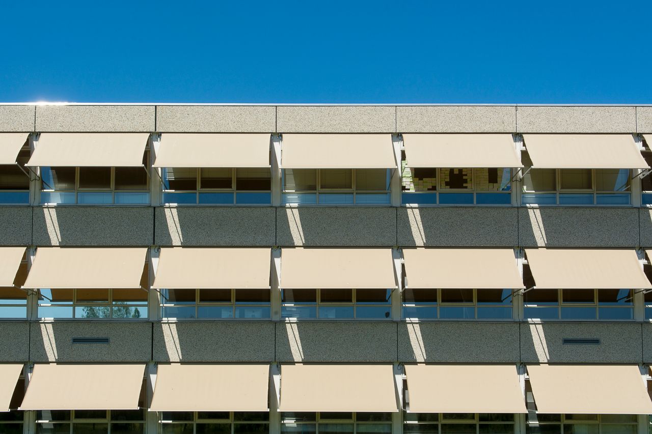 The Art of Drawing Readers In: Your attractive post title goes here Facade of a modern residential building with sun shades under a clear blue sky.