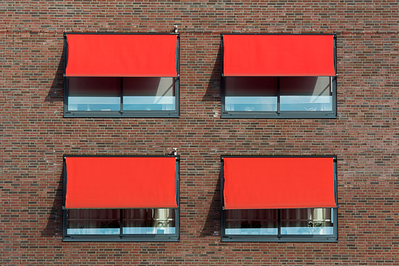 Mastering the First Impression: Your intriguing post title goes here Symmetrical brick wall with four red sun shades covering windows.